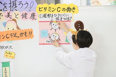 写真：移動式ホワイトボードに資料を貼り付ける学生