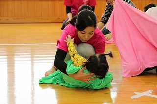 写真：幼児を毛布と一緒に抱えてしゃがむ学生