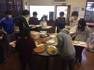 写真：バイキング形式で並べられたおかずを取る学生たち