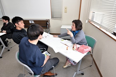 写真：熱心に説明する教員1人と学生2人