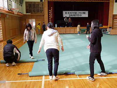 写真：準備の様子。体育館にシートを敷く学生