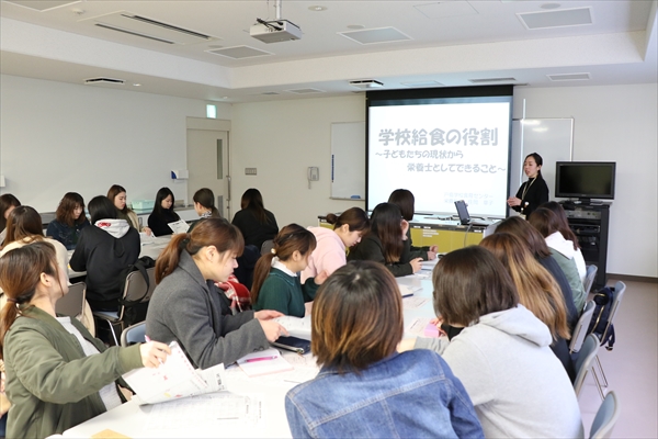 写真：住岡先生が大勢の学生を前にスライドを使って話す様子