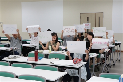 紙にメッセージを書いて掲げる学生