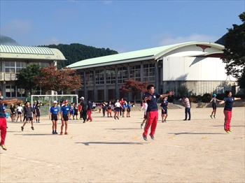 写真：列になって準備運動をする大学生と小学生