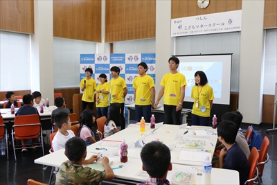 写真：学生6名が児童の前に立って挨拶をしている様子