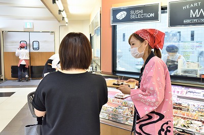 写真：地元スーパーマーケットのマルイの店頭で試食を片手に販売キャンペーンを実施