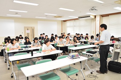写真：前にたって講義をする作野先生。その話を熱心に聞く学生たち