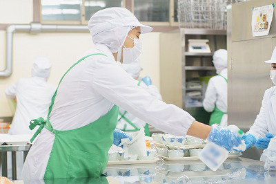 写真：盛り付け用の作業机を清掃する学生