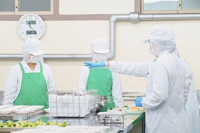 写真：大量調理中。作業手順について確認する学生たち