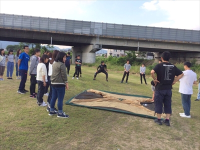 写真：河川敷でテントの立て方を部員にレクチャーする学生