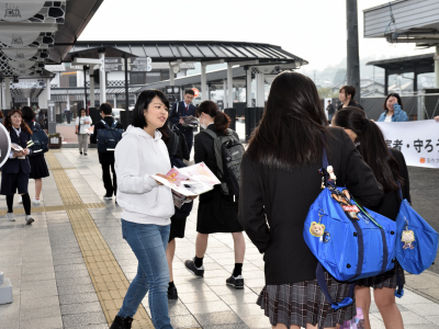写真：高校生にチラシを配る学生1人