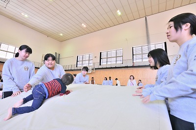 写真：マットでできた山を登る子どもと安全を確認しながら見守る学生