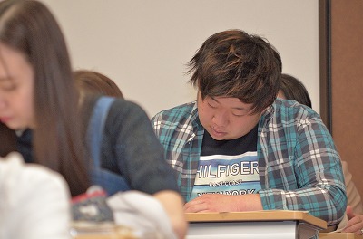 写真:熱心にメモを取りながら話を聞く男子学生