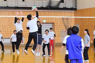 写真：バレーボールでアタックを打つ学生とブロックに飛ぶ学生
