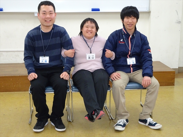 写真：参加者と学生が笑顔で腕を組んでいる様子