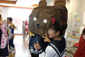 写真：巨大な熊の被り物をしている学生と制服を着ている学生