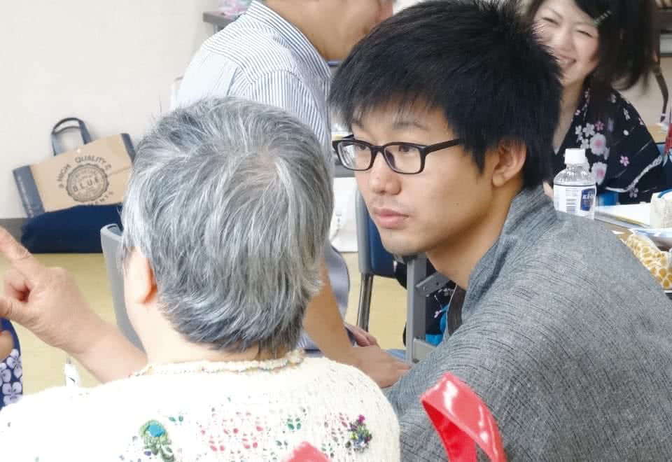 写真：福祉ボランティアでシニアの女性に顔を向ける男子生徒