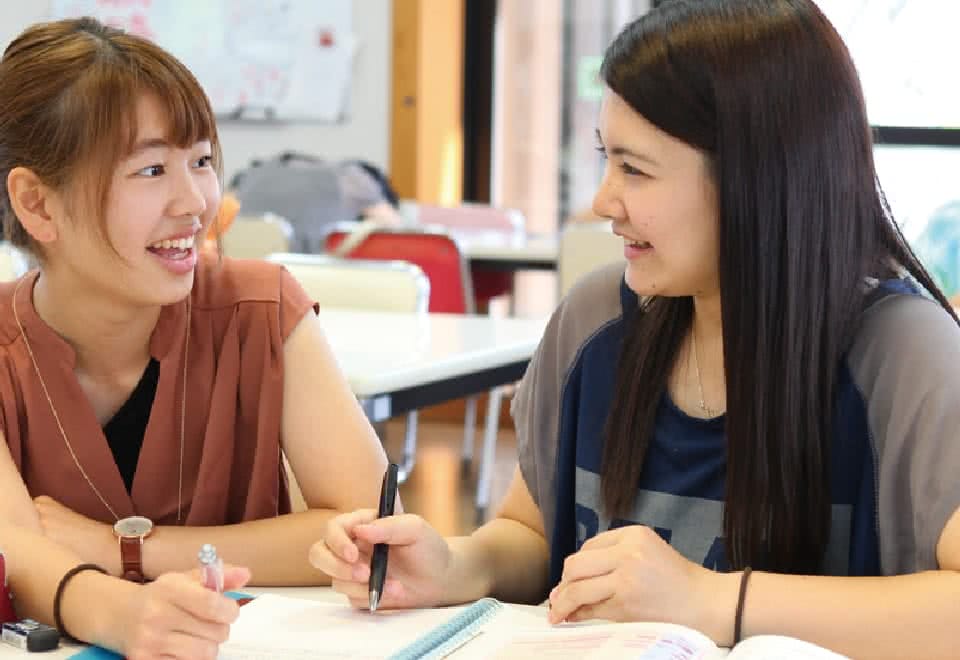 写真：笑顔でノートを広げている二人の女子生徒