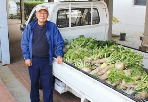 写真：軽トラックに積まれたたくさんの大根とその前に立つ美作学園 藤原理事長
