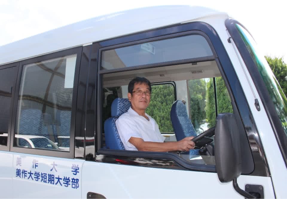 写真：；送迎バスに乗る男性の校務員さん