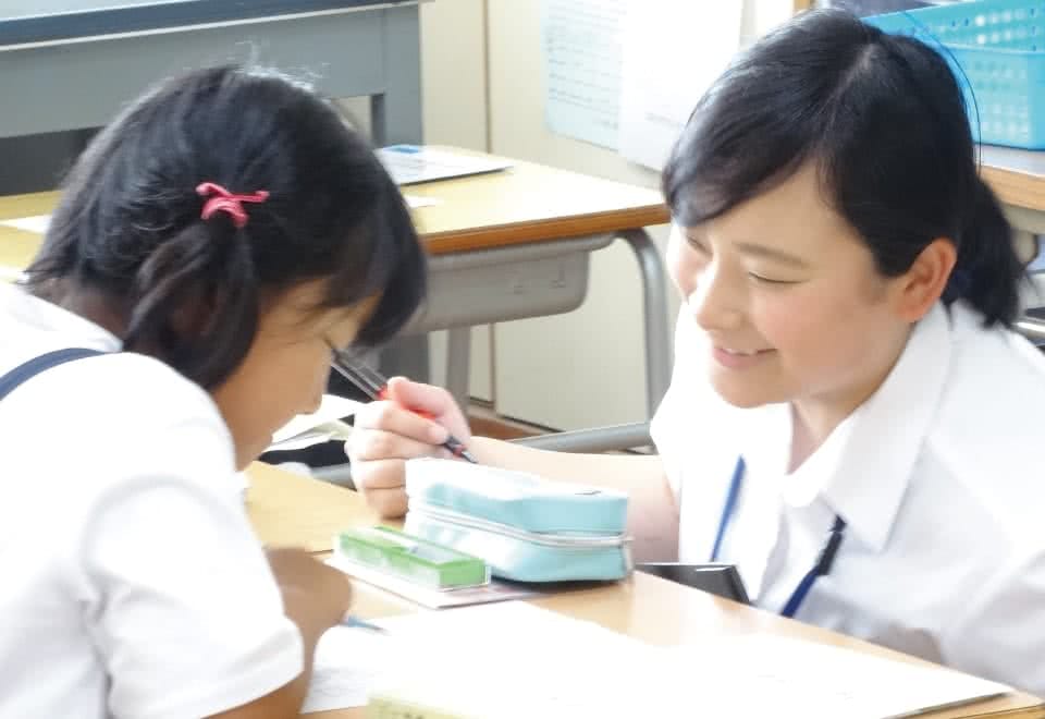 写真：授業支援として女子小学生に指導をする女子生徒