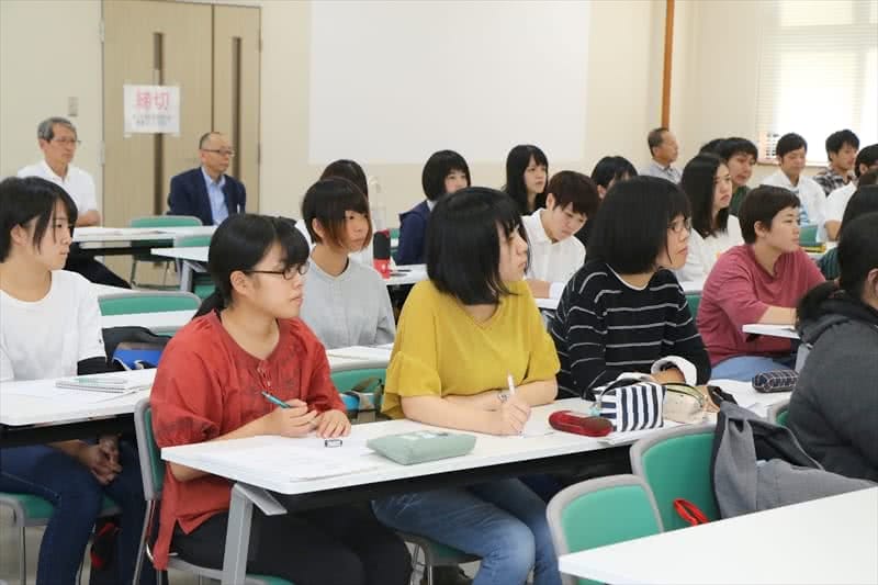 写真:メモを取りながら熱心に話を聞く3名の女子学生