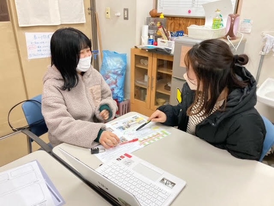 写真：和やかな雰囲気の中、資料やパソコンを使いながら親身に相談対応をする女性二人