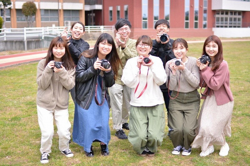 写真：美作大学のグラウンドでカメラを持ったメンバーの集合写真