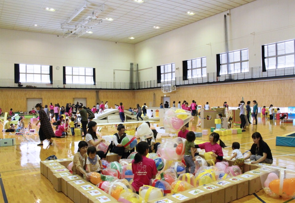 写真：体育館に設置された様々な手作りの遊具で遊ぶ大勢の親子と対応する学生たち