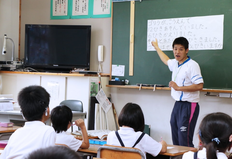 写真：小学校で教壇に立つ学生