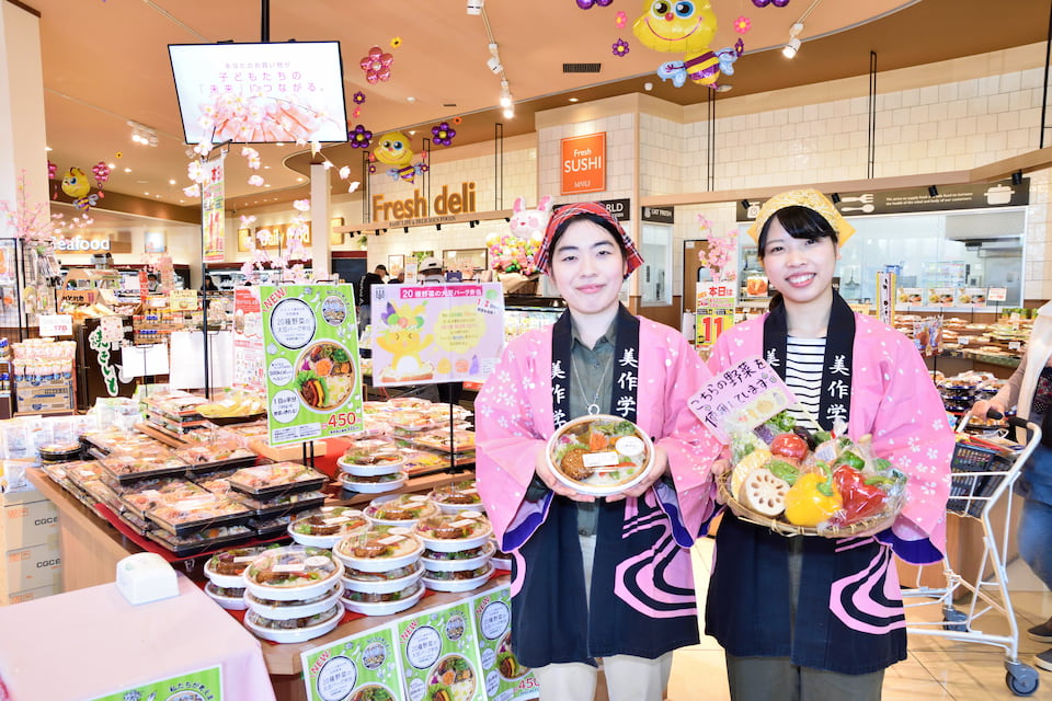 写真：マルイノースランド店にて実施した共同開発弁当販売キャンペーンでハッピを着て活動する人見研究室の学生たちと人見准教授