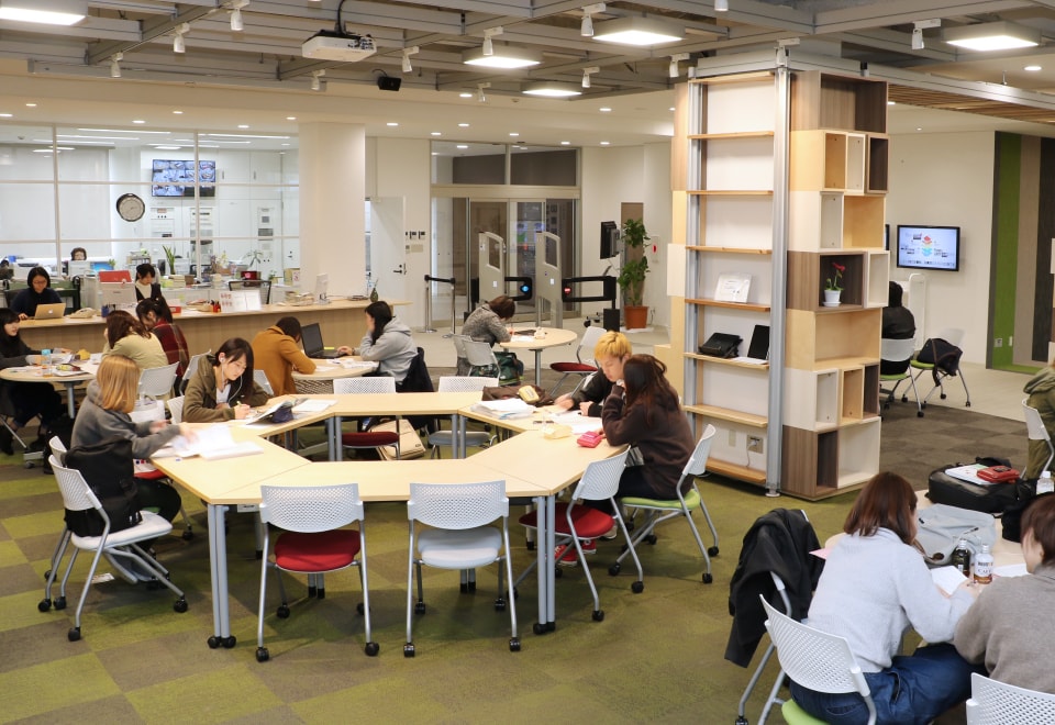 写真：ラーニング・コモンズの机で勉強をしている学生たち・机は六角形に組み合わされている。