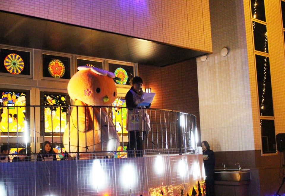 写真：サークルコモンズの半円ステージにいるみまっぱちゃんとマイクを持った女子学生。