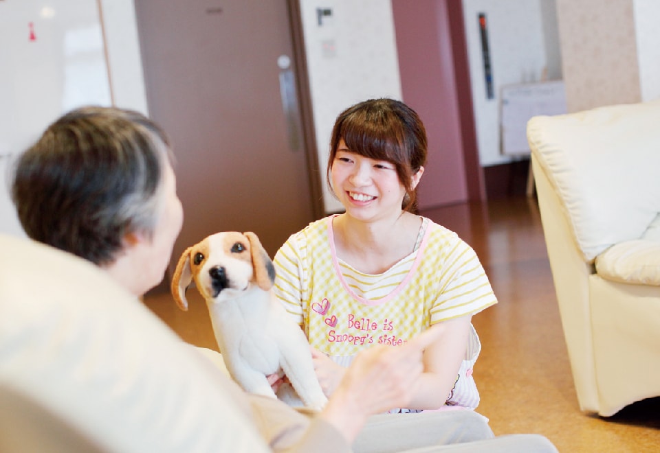 写真：女性が犬と一緒に患者さんにむかって笑顔で接している様子