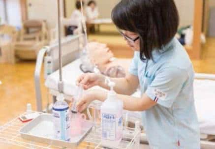 写真：介護用の器具で水を測り取る学生