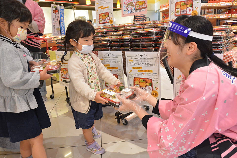 写真：子どもに弁当を手渡しする学生