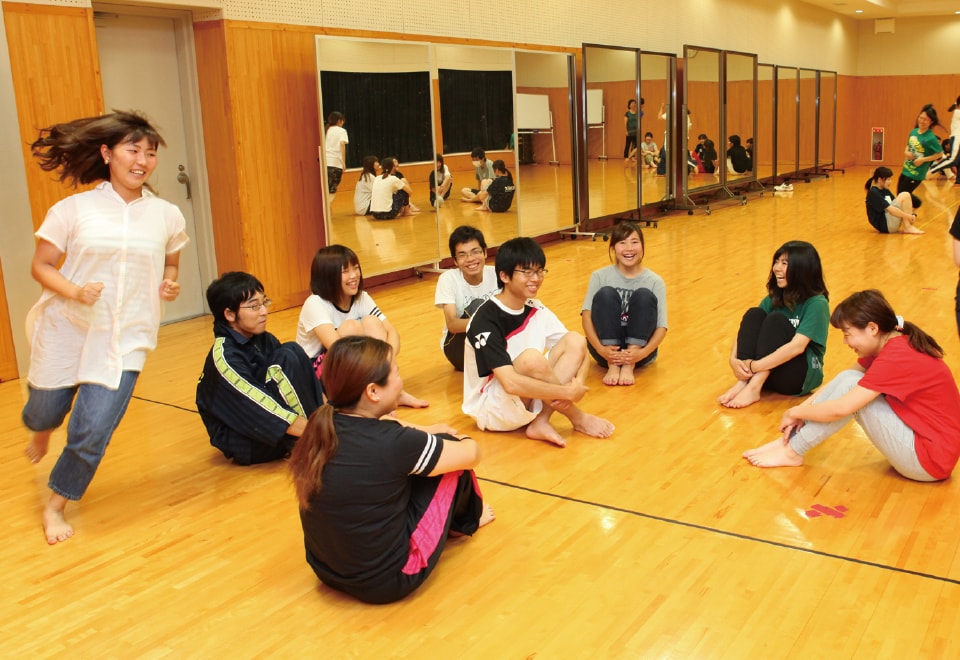 写真：円になりハンカチ落としゲームをする学生