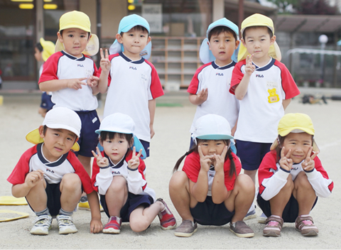 写真：8人の園児が並んでピースサインをしている様子