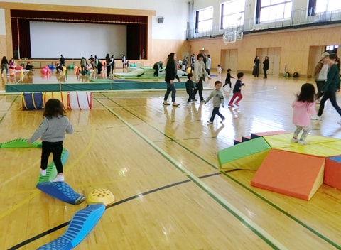 写真：屋内で風船を使った遊びを楽しむ子どもたちと保護者たち