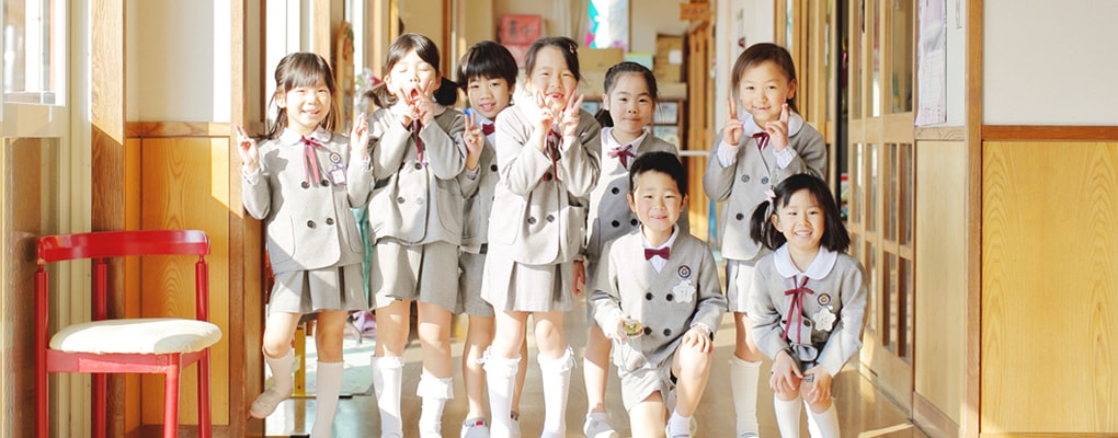 写真：園舎の廊下で集合写真に収まる8人の園児たち